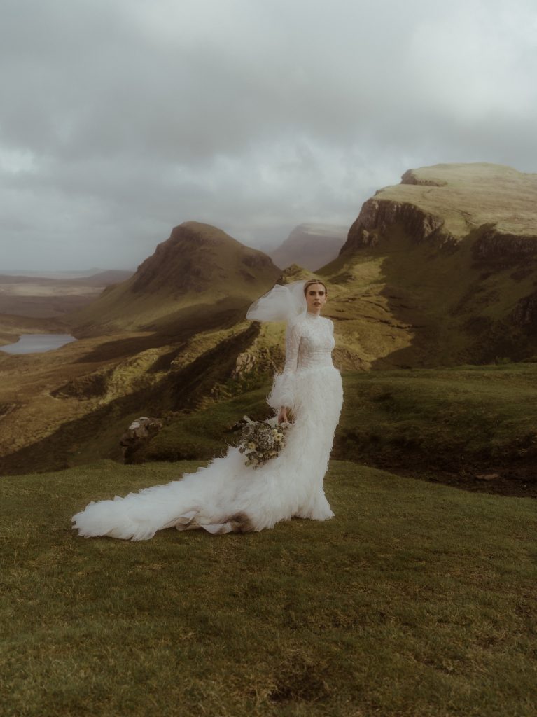 bride on top of Quiraing in a feather dress.